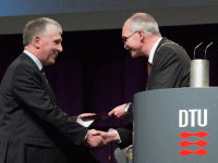 man presenting award and shaking hands with another man